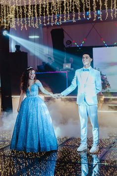 a man and woman dressed in formal wear holding hands while standing on a dance floor