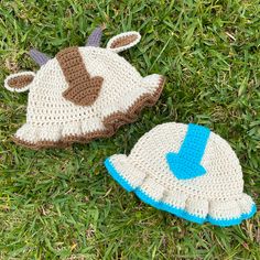 two crocheted hats laying on the grass