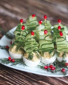 deviled eggs topped with cucumbers and christmas greenery on a white plate