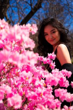 a woman is posing in front of pink flowers