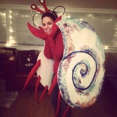 a woman dressed up as a snail and holding a giant candy lollypopo