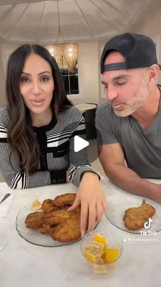 a man and woman sitting at a table with plates of fried food in front of them