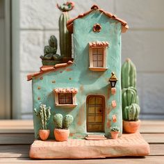 a clay house with cacti and succulents around it