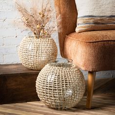 two decorative vases sitting on top of a wooden floor next to a brown chair