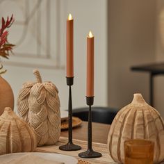 three candles are sitting on a table next to other decorative objects and pumpkins in the background