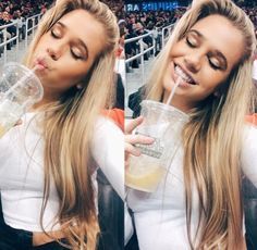 a woman drinking from a plastic cup while sitting in front of a crowd at a basketball game