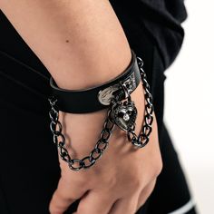 Black Leather Wristband with Heart Padlock Elevate your style with our Black Leather Wristband, measuring 8.5 inches in length and 1.75 inches in width. This piece features a stained metallic chain and a heart-shaped padlock, adding a touch of edgy elegance to your look. Designed for comfort and versatility, this wristband is not too bulky, making it perfect for daily wear. Whether you're dressing up or keeping it casual, this wristband is a standout accessory that complements any outfit. Edgy Elegance, Heart Padlocks, Leather Wristbands, Bracelet Collection, Heart Bracelet, Alternative Fashion, Leather Straps, Daily Wear, Black Leather