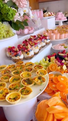 an assortment of desserts and pastries are displayed on a buffet table with flowers