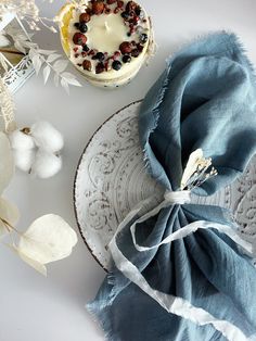 a table topped with a plate covered in cake next to a blue napkin and cotton