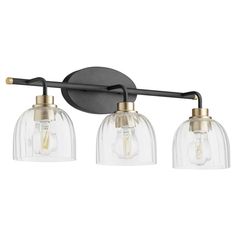 three light bathroom fixture with clear glass shades and gold accents on an aged black wall