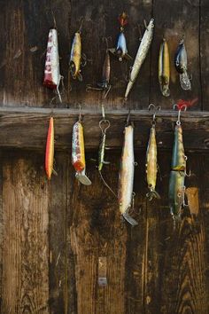 several different types of fishing lures hanging on a wooden wall