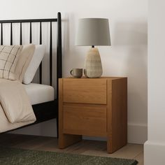 a bedroom with a bed, night stand and lamp on the nightstand next to it