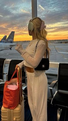 a woman is standing on the deck of an airplane with her suitcase and headphones