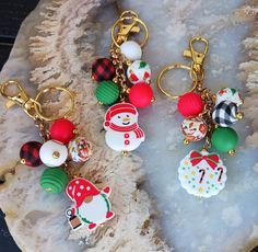 three christmas themed key chains sitting on top of a rock