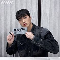 a young man holding up a sign that says venue 101 in front of his face