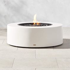 a fire pit sitting on top of a tile floor next to a wall with white walls