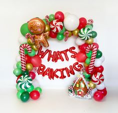 the balloon arch is decorated with candy canes, gingerbread man and what's baking sign