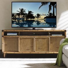 a flat screen tv sitting on top of a wooden entertainment center next to a white couch