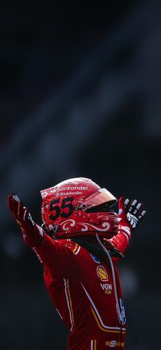 a man in red is holding his hands up to the sky and wearing a helmet