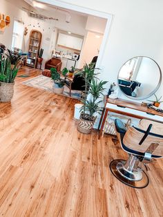 a living room filled with furniture and lots of plants on top of wooden flooring