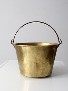 an old brass bucket sitting on a white surface