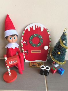 two elfs sitting next to each other near a christmas tree, mailbox and door