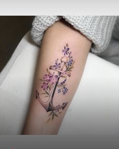 an anchor and flowers tattoo on the arm