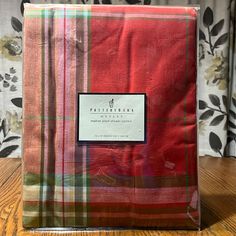 a red and green plaid blanket sitting on top of a wooden table