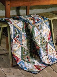 a quilt draped over a wooden bench on the floor