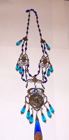 This an outstanding turquoise and cobalt blue Czechoslovakian bib necklace. The design and their attention to detail truly exemplify their craftsmanship. The necklace measures 16 in length and is stamped on the reverse side of the large medallion. This exquisite necklace is in excellent Blue Bohemian Medallion Necklace, Bohemian Blue Medallion Necklace, Antique Blue Medallion Necklace, Antique Blue Jewelry With Large Pendant, Ornate Blue Pendant Necklace, Blue Medallion Pendant Jewelry, Blue Medallion Jewelry With Large Pendant, Antique Blue Pendant Necklace, Victorian Blue Jewelry For Jewelry Making