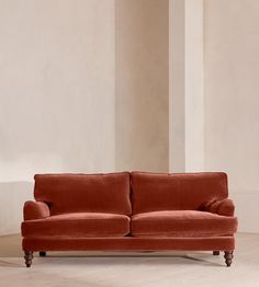 an orange couch sitting in a room next to a tall white wall and wooden legs