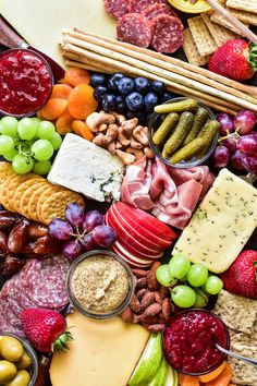 an assortment of cheeses, meats, fruit and crackers on a platter