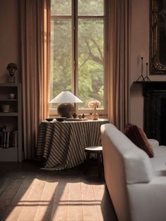 a living room filled with furniture and a lamp on top of a table next to a window