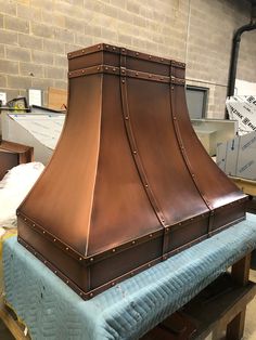 a large copper range hood sitting on top of a table