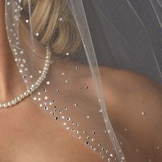 a woman wearing a veil with pearls on it