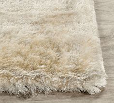 an area rug with white shag on top of wooden flooring and wood floors