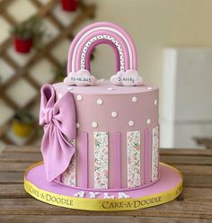 a pink cake with white polka dots and a bow on the top that is shaped like a purse