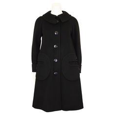 This Pierre Cardin black wool coat from the 1960s is a striking and iconic piece of fashion from the era. It exemplifies Cardin's avant-garde approach to design and his innovative vision of futuristic fashion. Made from high-quality black wool, which was a popular and luxurious fabric choice during the 1960s. The coat has a swing silhouette with clean lines and a modern, minimalist aesthetic. The length hits just below the knee, providing both style and warmth. The most notable features are the Black Wool Coat, Futuristic Fashion, Coat Black, Minimalist Aesthetic, Pierre Cardin, The 1960s, Outerwear Coats, Black Wool, Luxury Fabrics