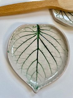 a white and green leaf shaped dish next to a wooden spoon