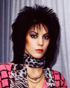 a woman with black hair wearing a pink shirt and leopard print scarf around her neck