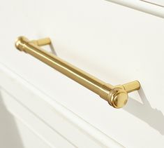 a close up of a handle on a white cabinet door with gold handles and knobs