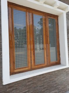 two wooden doors are open on the side of a brick building with white trim and windows