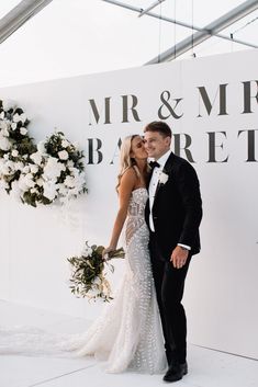 a newly married couple standing in front of a sign