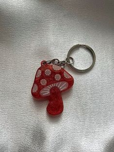 a red mushroom keychain sitting on top of a silver surface