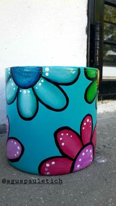 a painted flower pot sitting on the ground