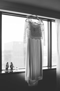 a wedding dress hanging in front of a window