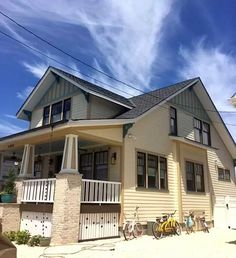 two bicycles are parked in front of a house on a sunny day with blue skies