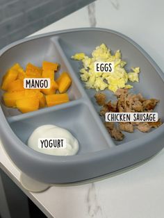 an image of a tray with food labeled on it that includes eggs, mangos, chicken sausage and yogurt