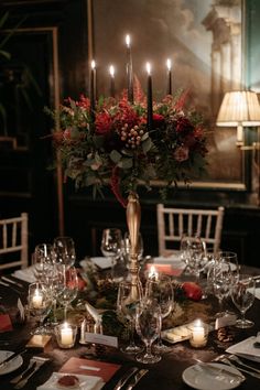 a centerpiece with candles and flowers on top of a table in a dining room