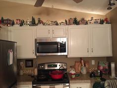 a kitchen with white cabinets and black stove top oven, christmas decorations on the wall above it